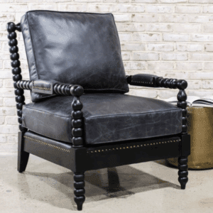 Black leather armchair with ornate wooden frame against a brick wall.